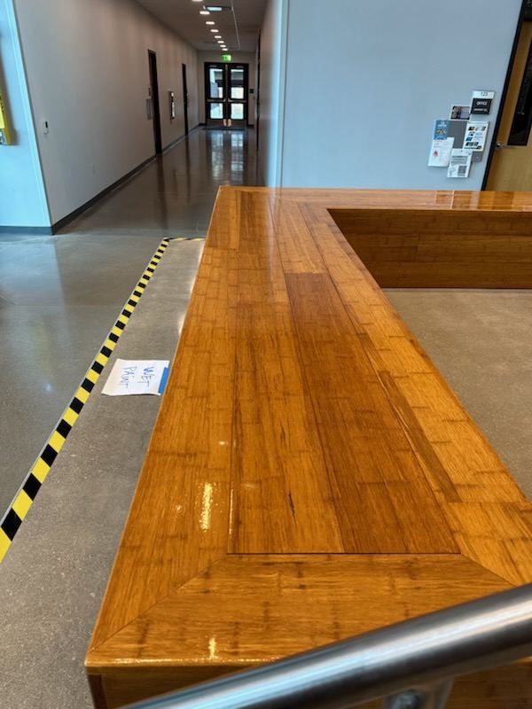 Finished bamboo reception counter with mitred edge detail installed in a commercial corridor